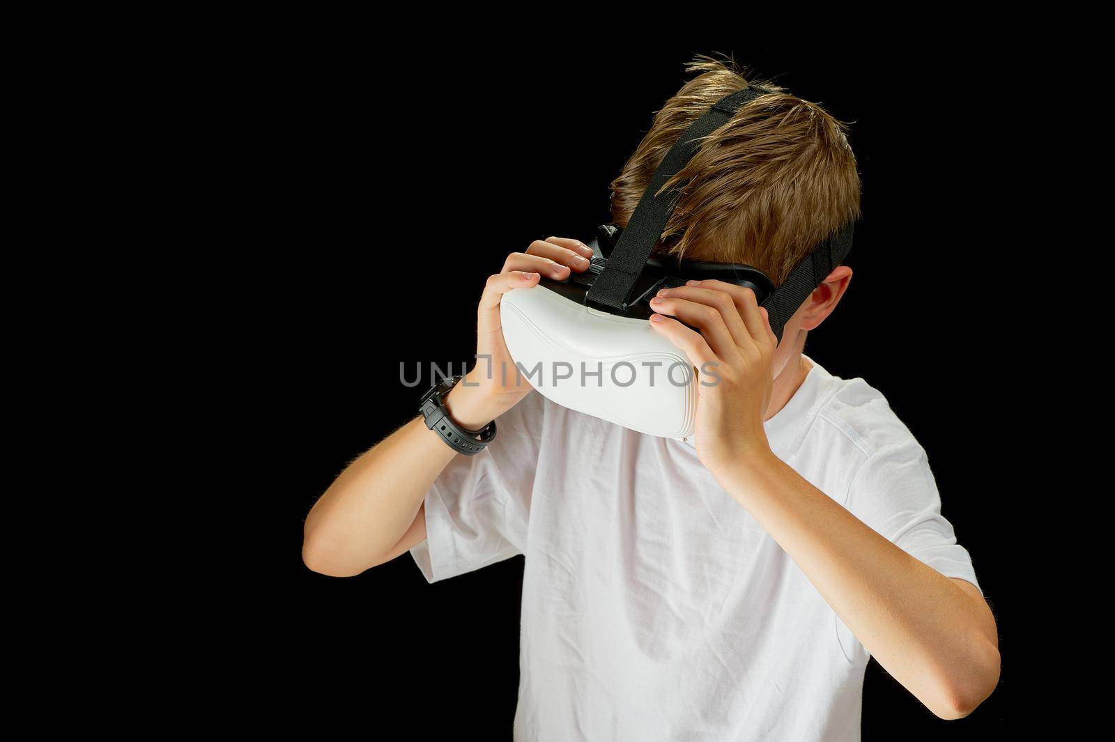 Portrait of young boy playing VR game in black background. Young hipster wearing VR headse by PhotoTime