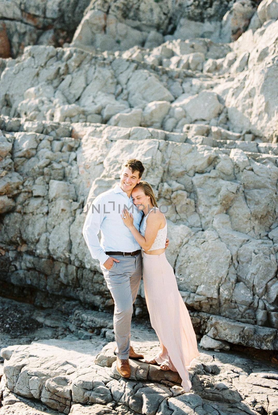 Young man and woman hugging standing on the rocks. High quality photo