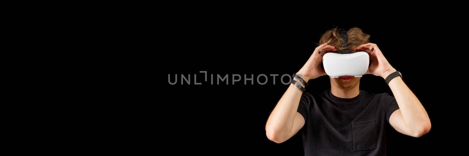 Portrait of a young man with 3D virtual reality glasses. Young man using white virtual reality headset, VR, future, goggles, technology concept on black background.