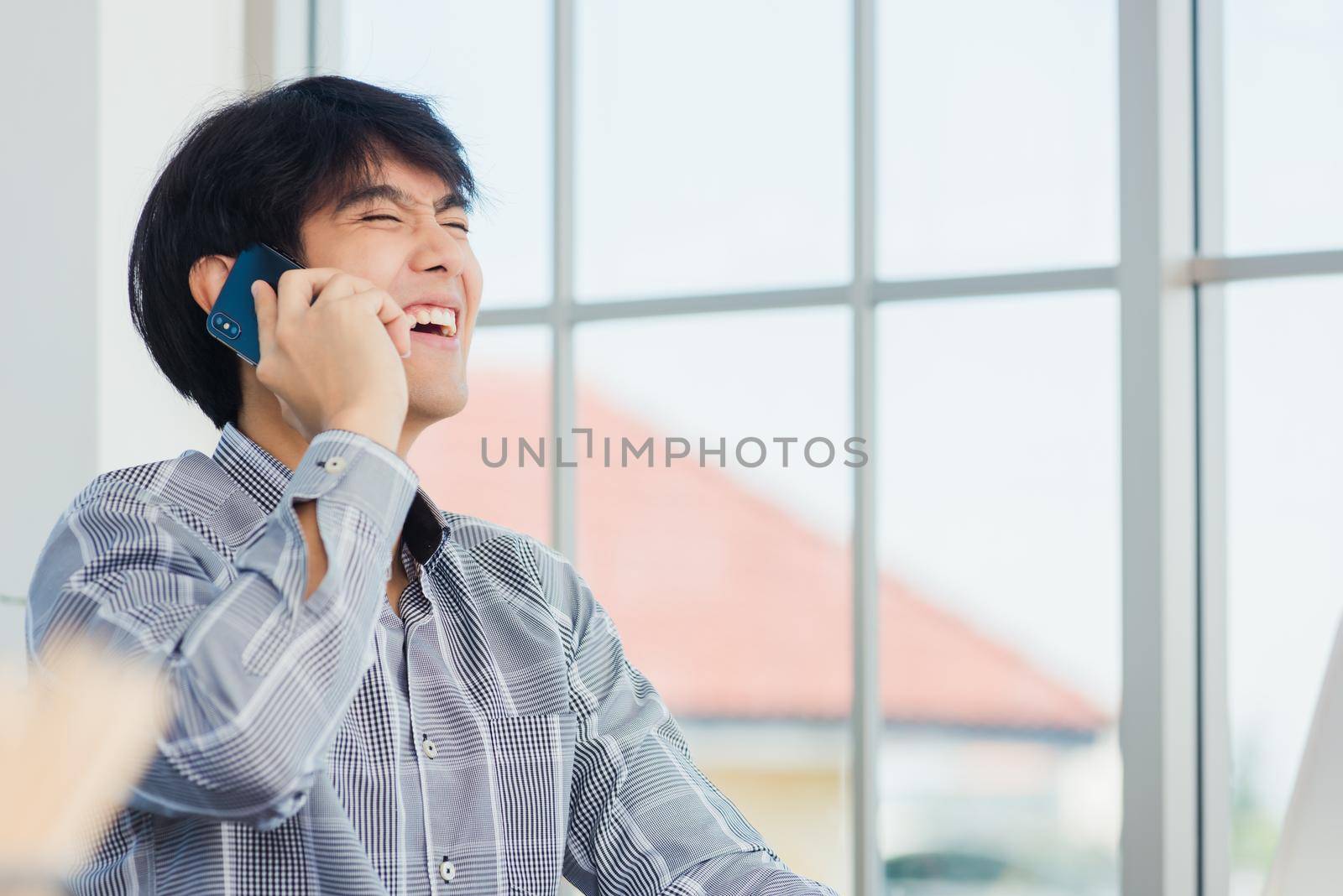 businessman smiling and talking on a mobile phone at home office desk by Sorapop