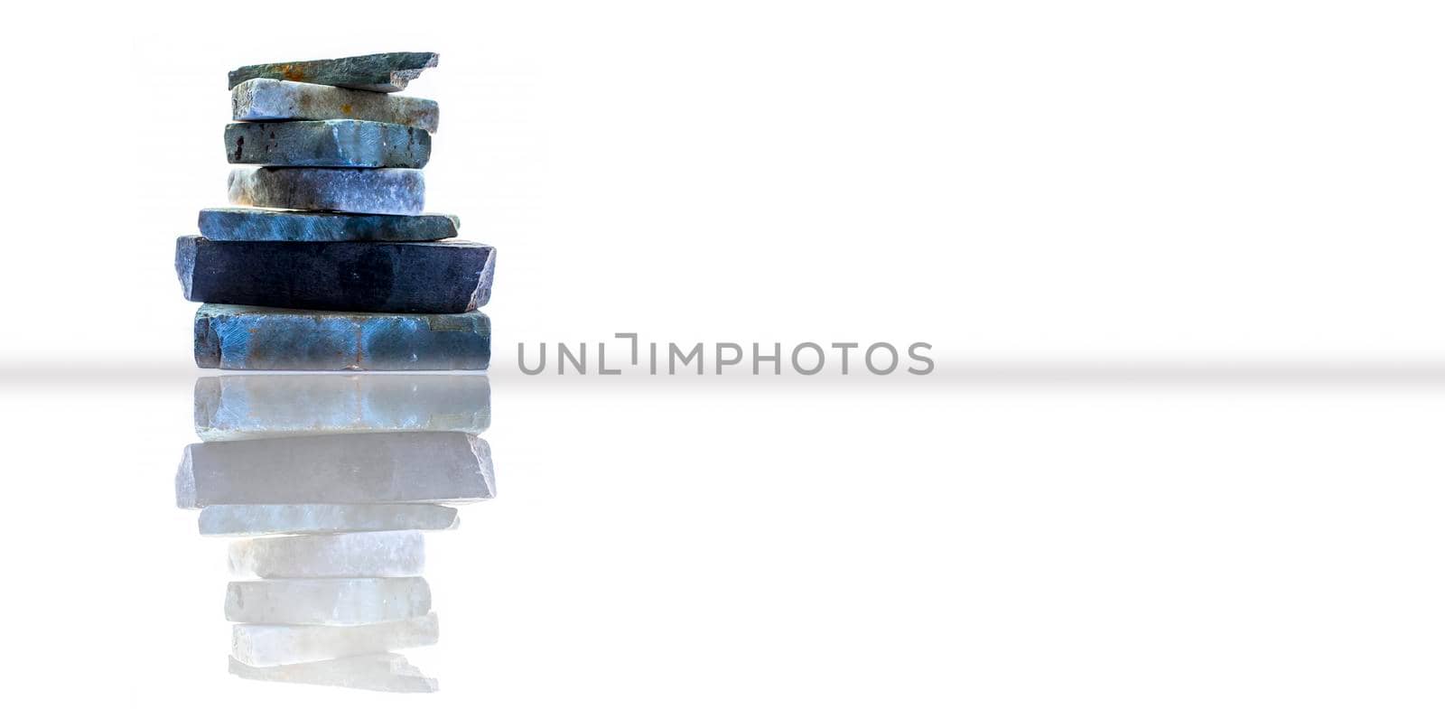 Horizontal shot of a bunch of rocks stacked on each other. Isolated on a white background along with its reflection.