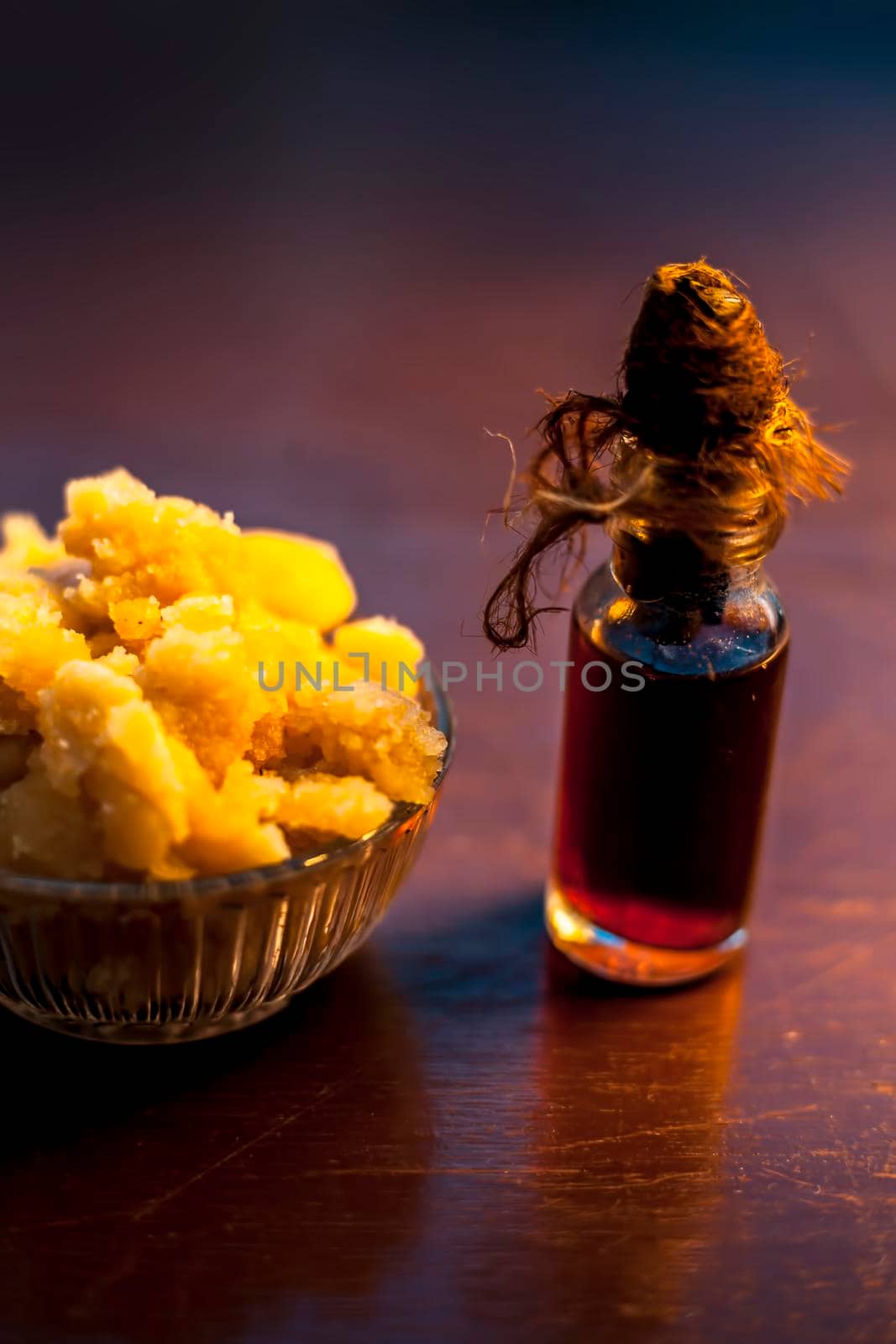 Close up of glass cup full of raw jaggery or gud or palm jaggery and its extracted oil in a glass bottle used for oil pulling in ayurvedic dental treatment. Vertical shot.