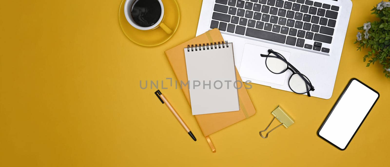 Top view stylish workplace with laptop computer, mobile phone, notebooks and coffee cup.