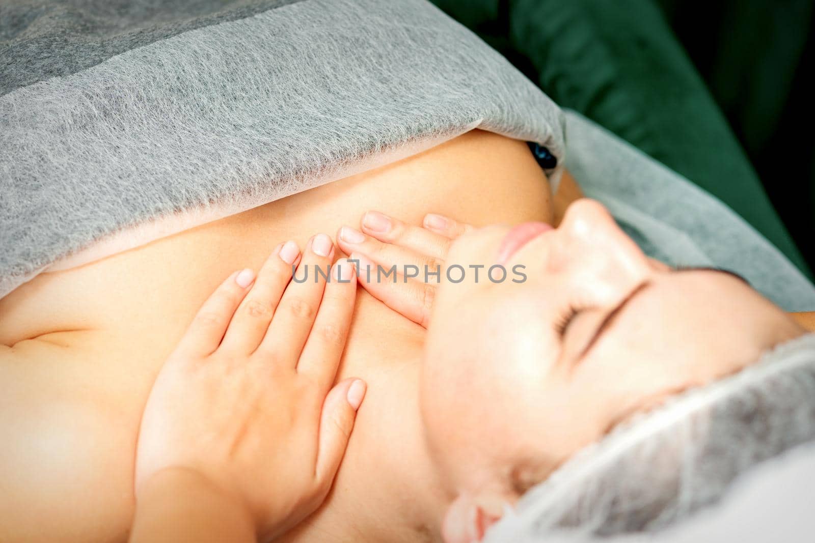 Masseuse makes a chest massage of a young caucasian woman in a spa salon