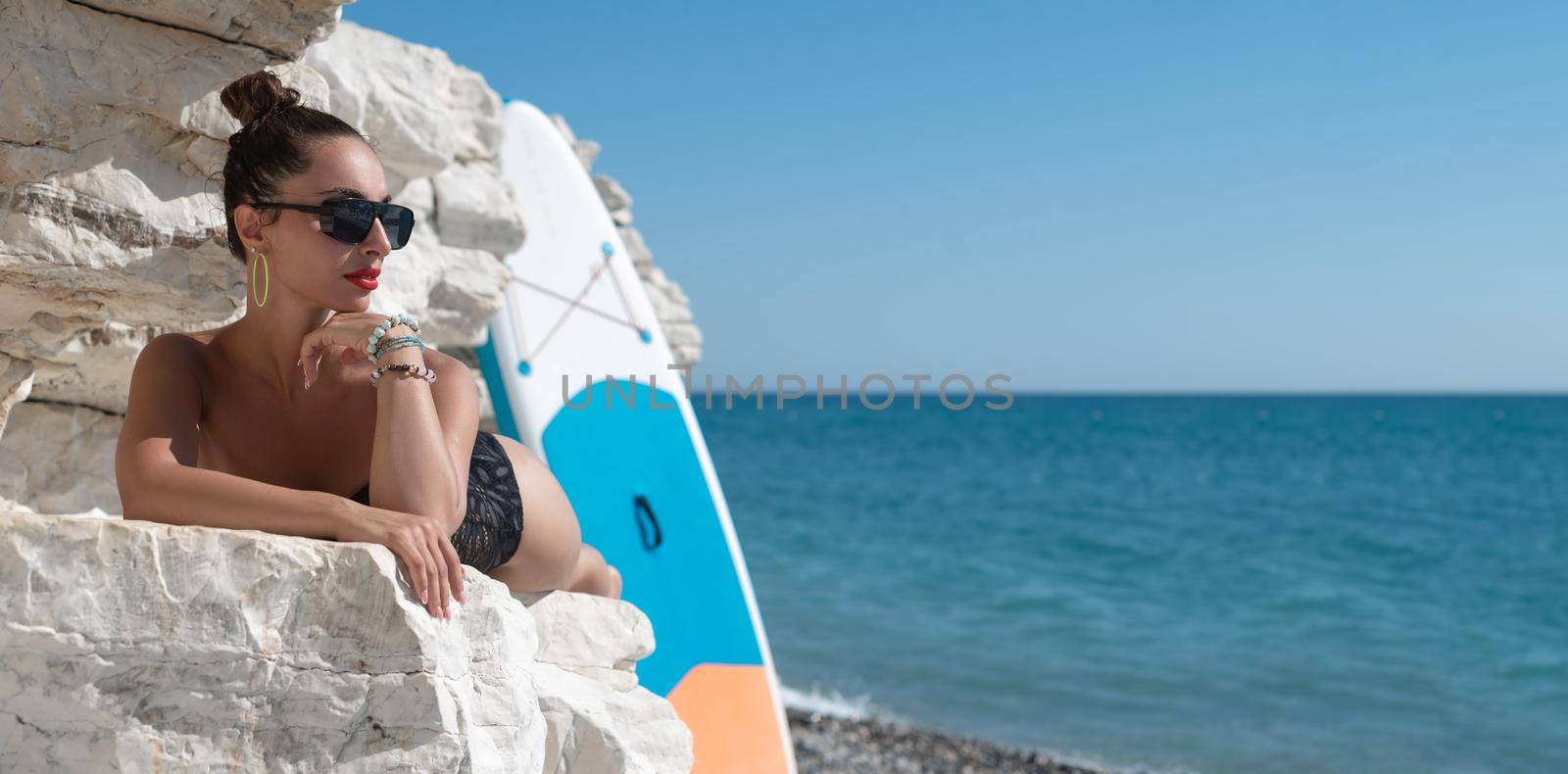sexy young girl in a swimsuit on a sup board by the sea in stylish sunglasses by Rotozey