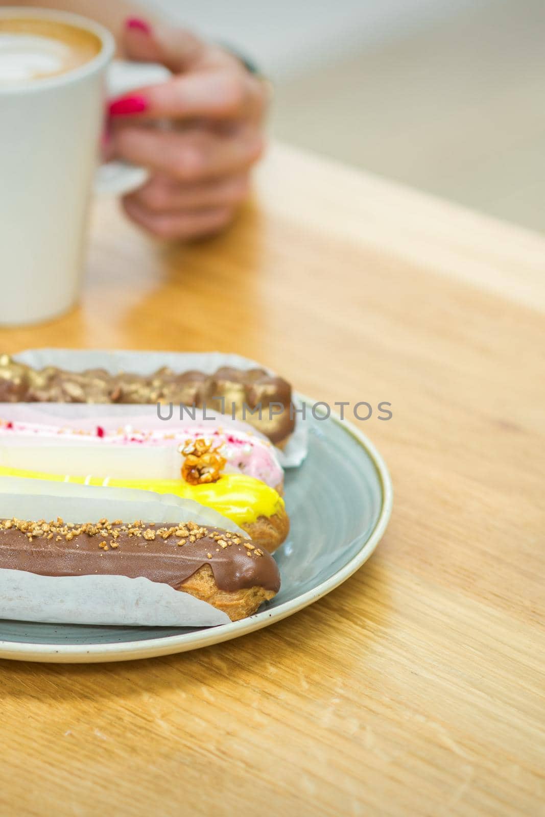 Young woman with cup of coffee and piece of cake sitting at the table in a cafe outdoors