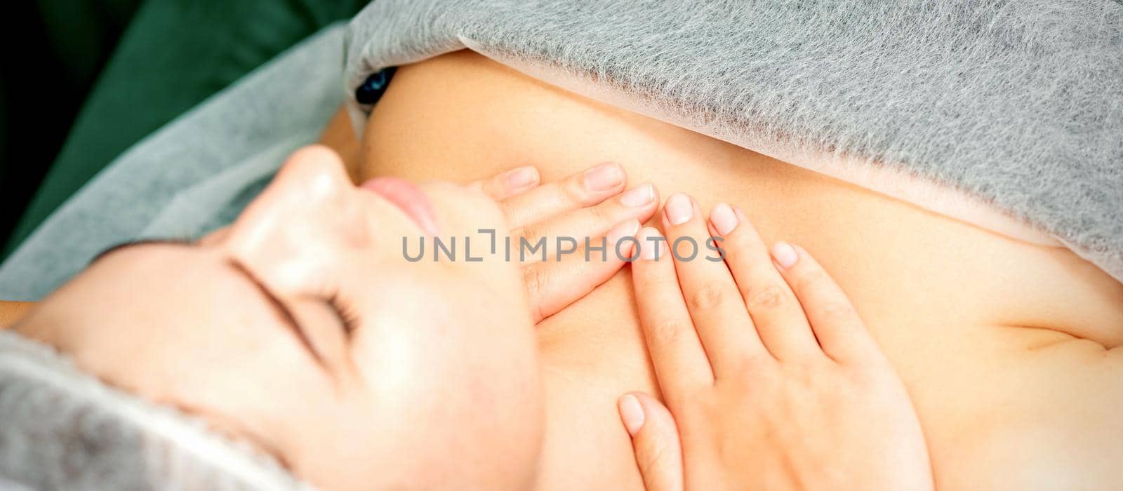 Masseuse makes a chest massage of a young caucasian woman in a spa salon