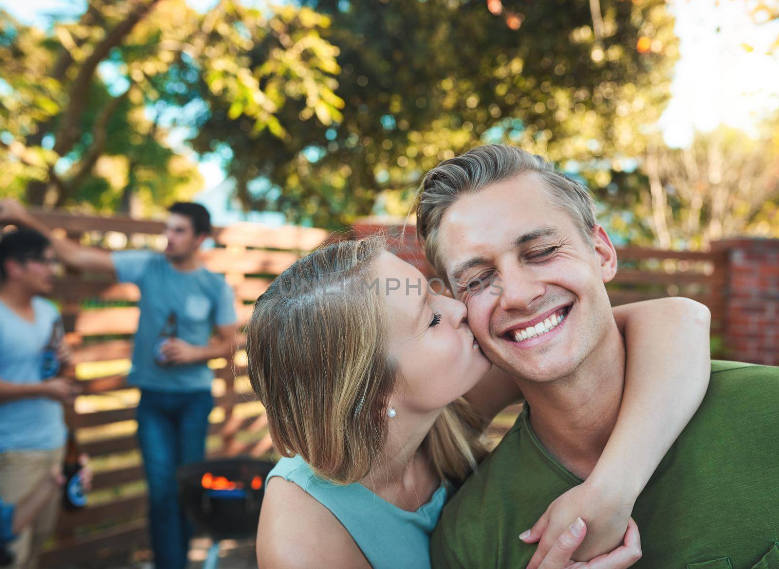 Love is contagious, pass it on. an affectionate young couple hanging out with their friends at a barbecue