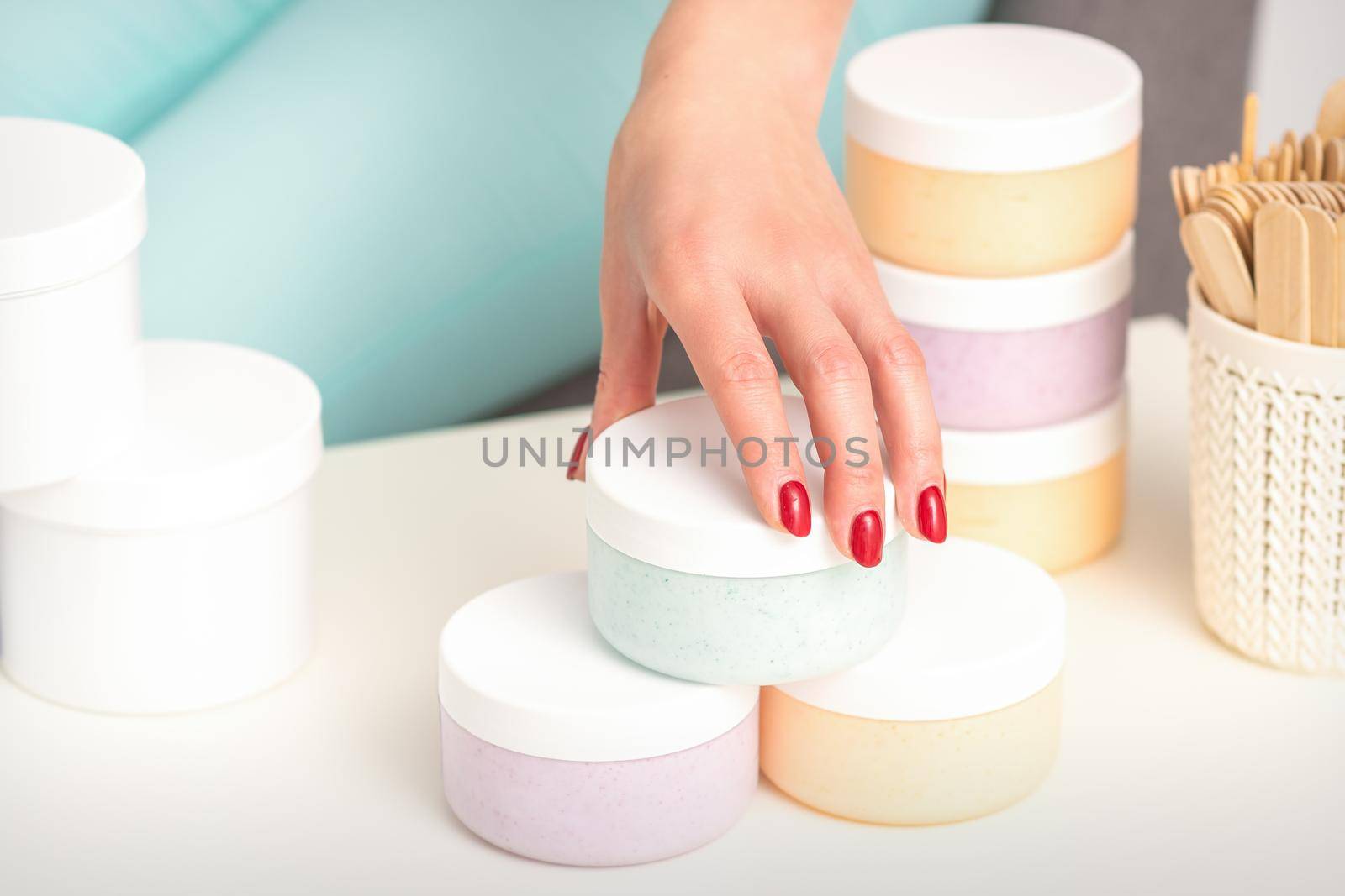 Beautician's hand takes jar with cosmetics from table offering and selling cosmetic products, moisturizing cream, wax paste