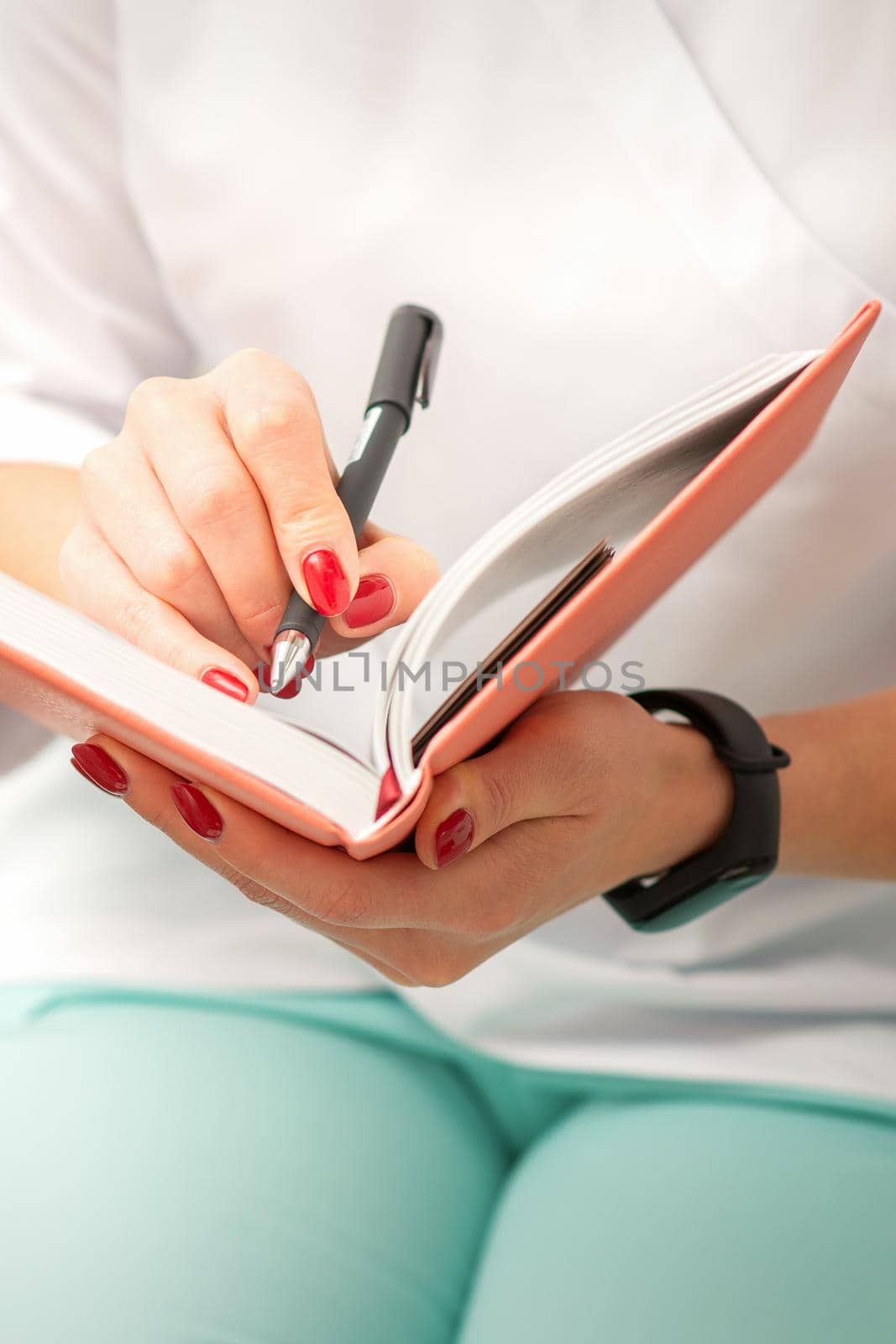 Close up of female doctor therapist writes notes in a medical notepad sitting in medical office