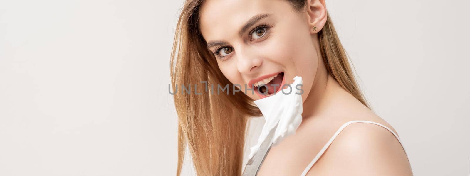 Portrait of young caucasian woman withg knife and shaving foam looking at camera on white background