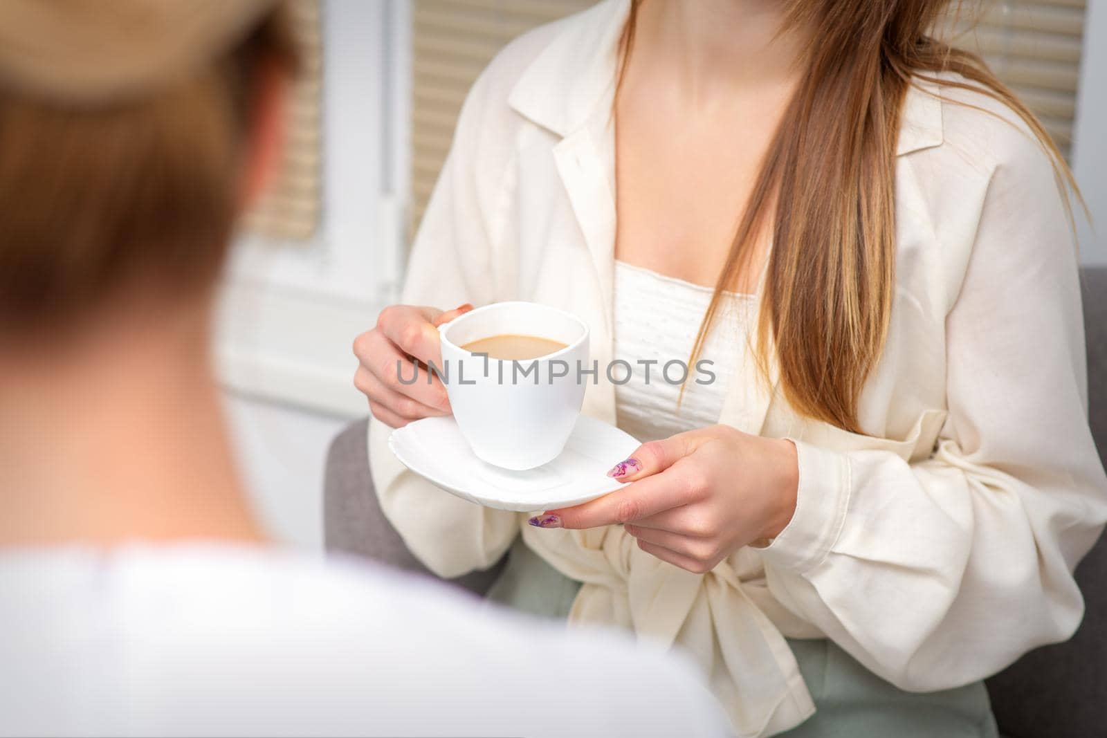 Young caucasian unrecognizable woman holding a cup of hot drink at a doctor's appointment in hospital office