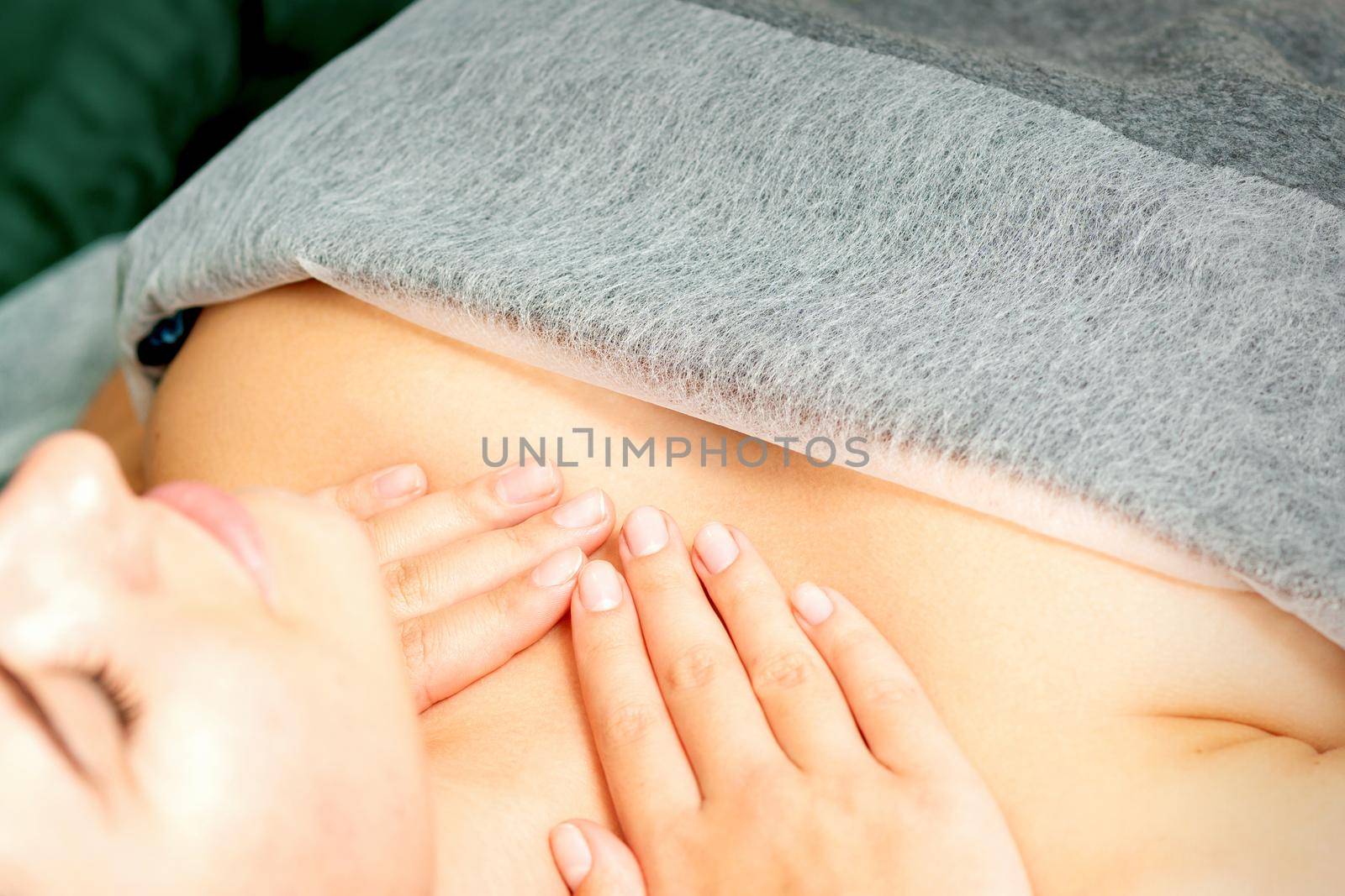 Masseuse makes a chest massage of a young caucasian woman in a spa salon