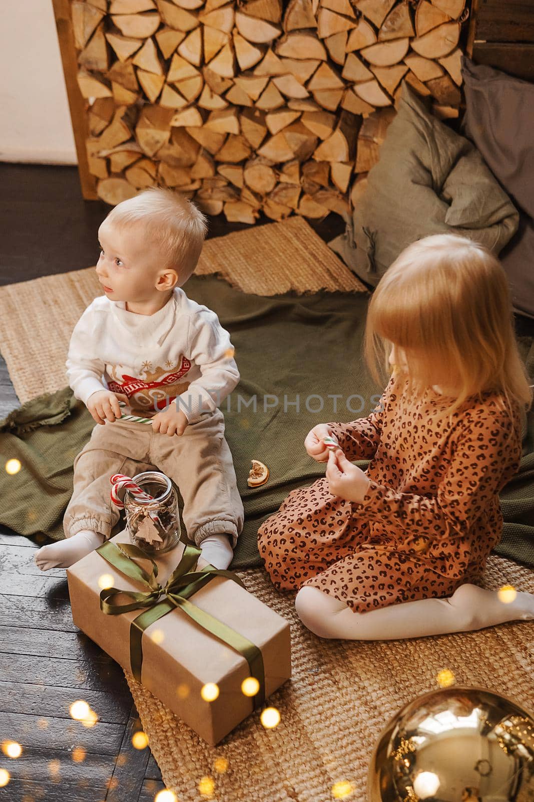 Little brother and sister play on Christmas eve in a beautiful house decorated for the New Year holidays. Children are playing with a Christmas gift. by Annu1tochka