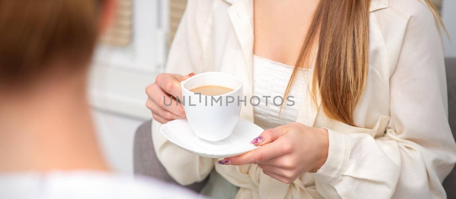 Young caucasian unrecognizable woman holding a cup of hot drink at a doctor's appointment in hospital office