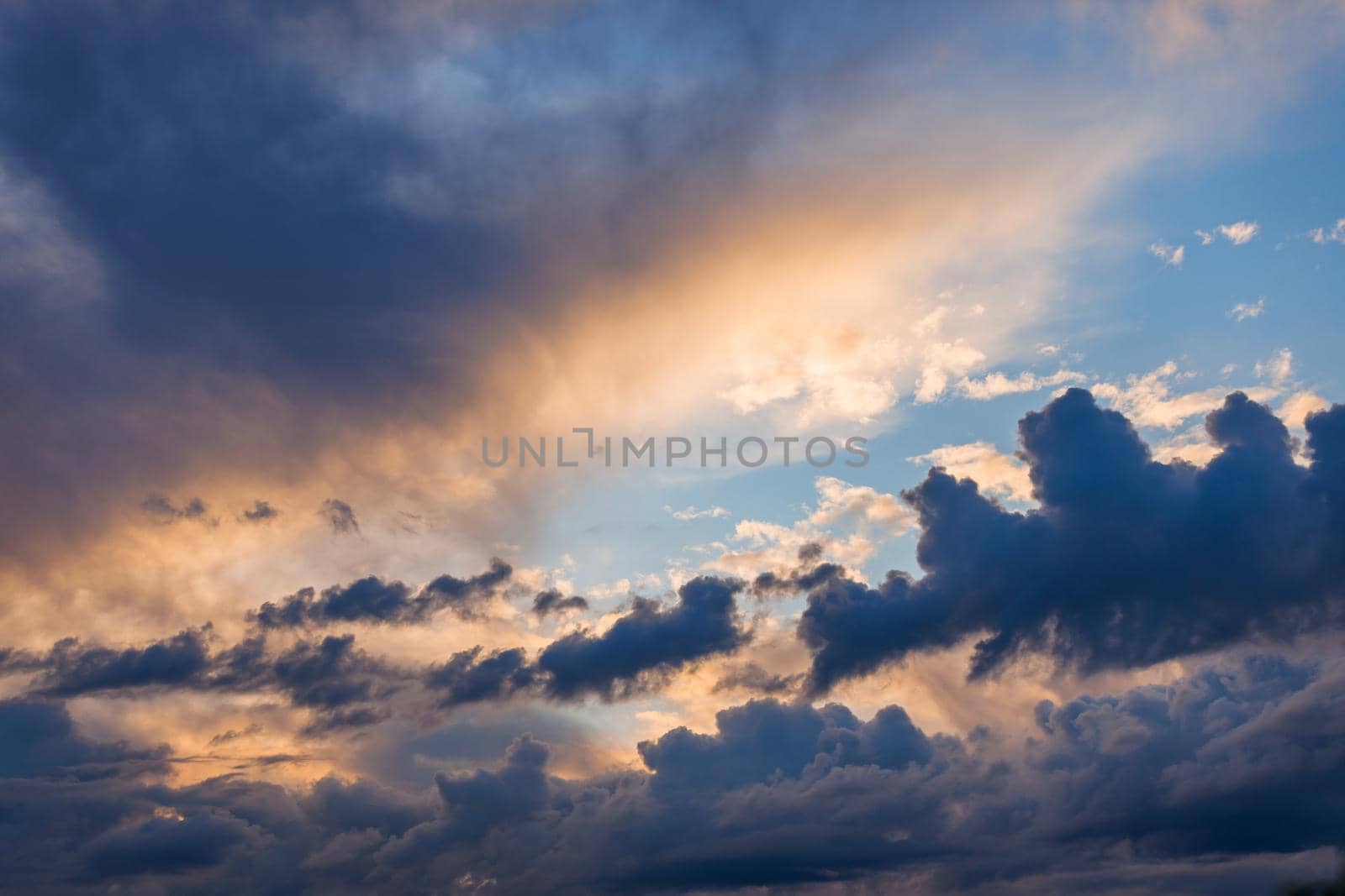 Cumulus clouds on evening sky backlit with sunset. Captured with 70mm lens on 35mm full-frame sensor camera.