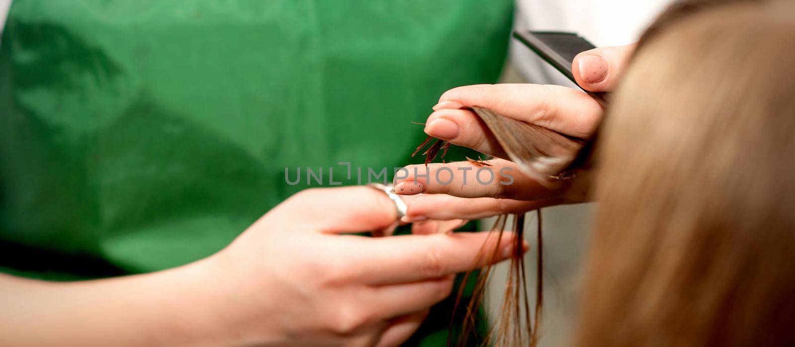 Closeup of a hairdresser cutting hair tips of a female customer in a beauty salon