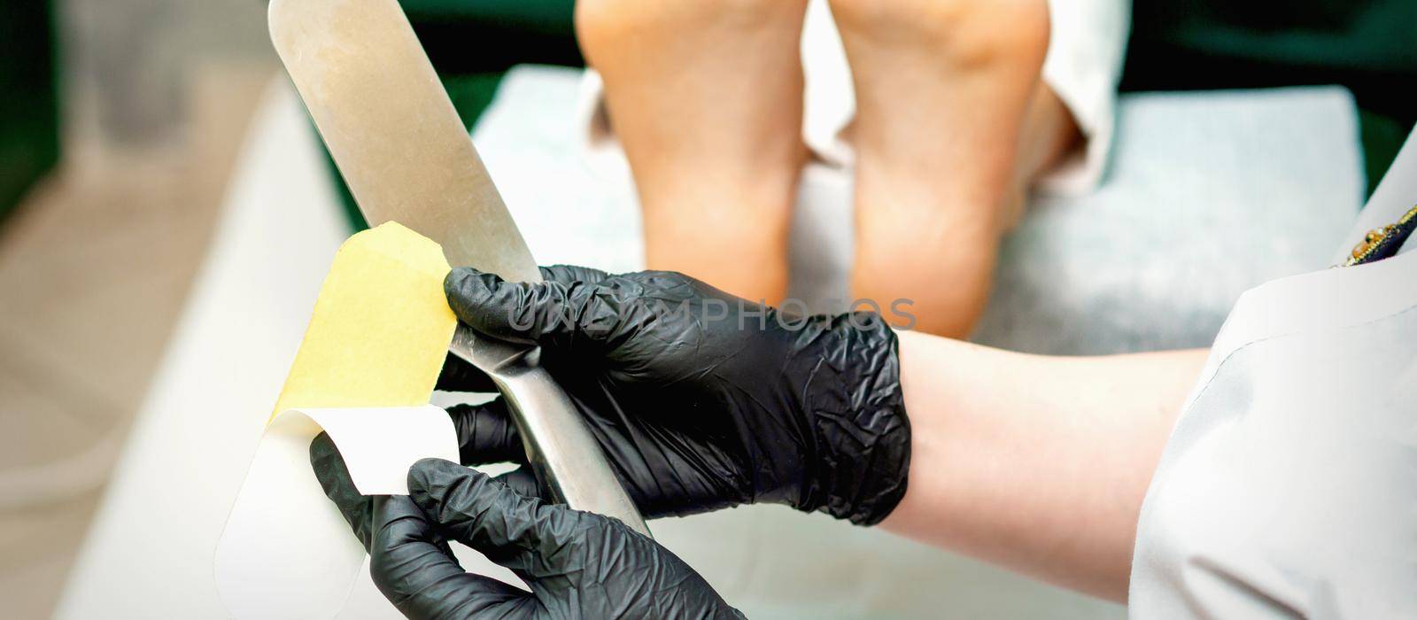 The pedicure master putting on new sandpaper on the metal handle before the procedure of cleaning the foot and heel in a nail salon