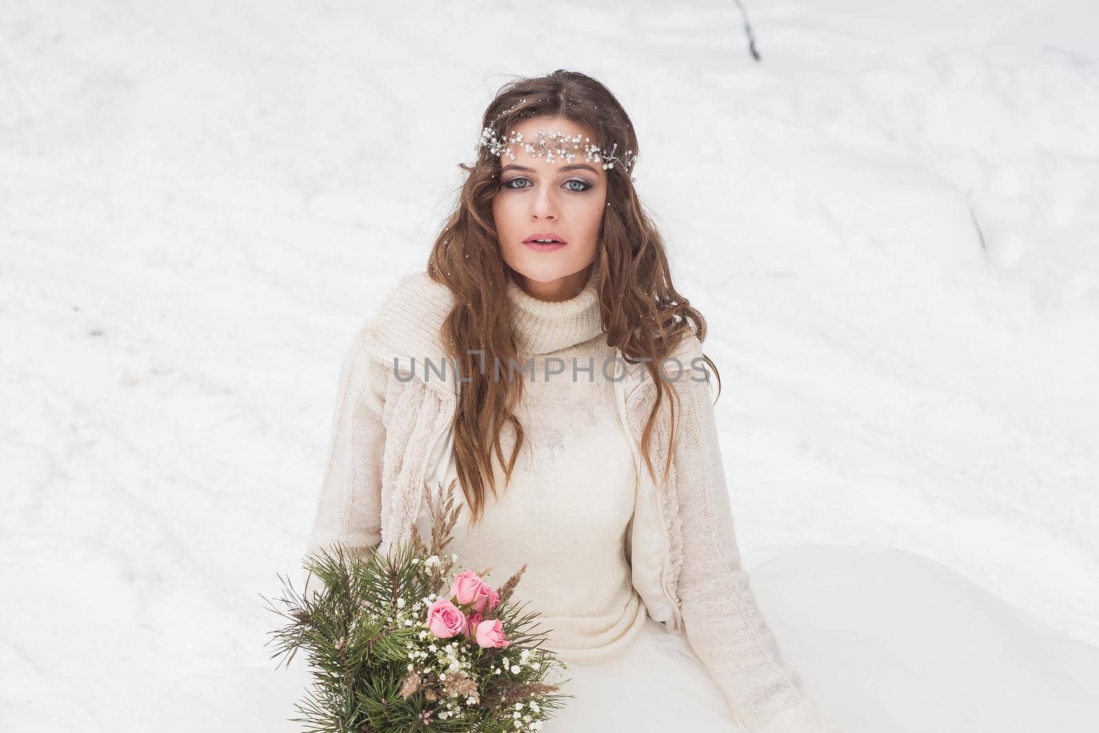 Beautiful bride in a white dress with a bouquet in a snow-covered winter forest. Portrait of the bride in nature.Beautiful bride in a white dress with a bouquet in a snow-covered winter forest. Portrait of the bride in nature.
