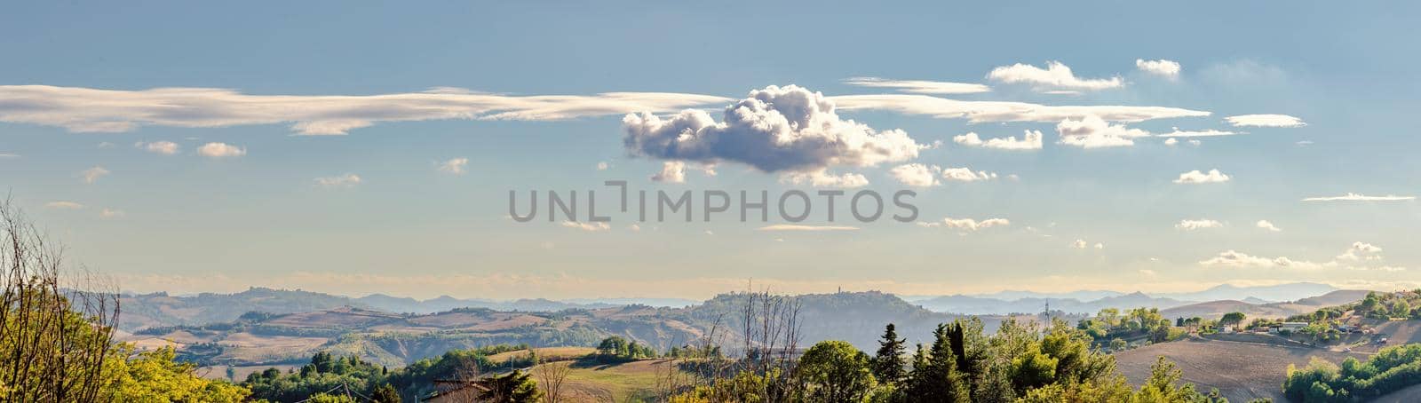 View of the Montefeltro hills and mountains from Belvedere Fogliense in the Marche region of Italy, at evening, under a cloudy sky.