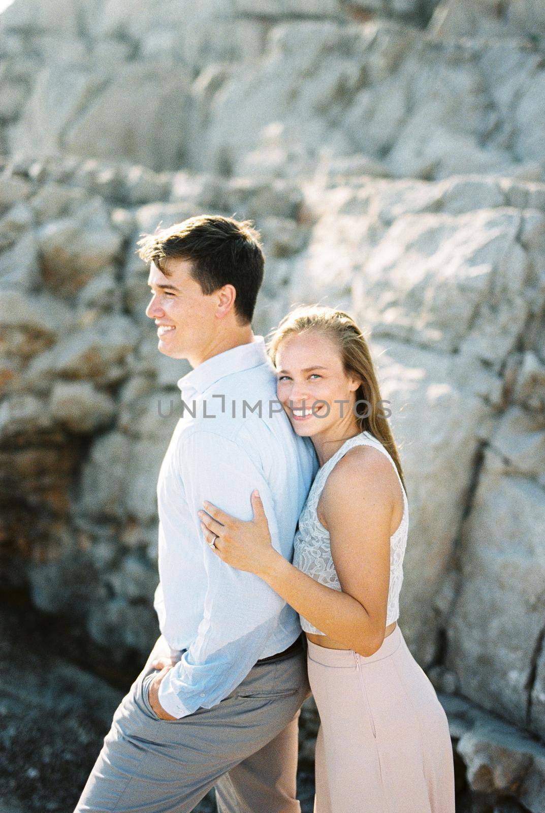 Smiling woman leaning against man from behind. High quality photo