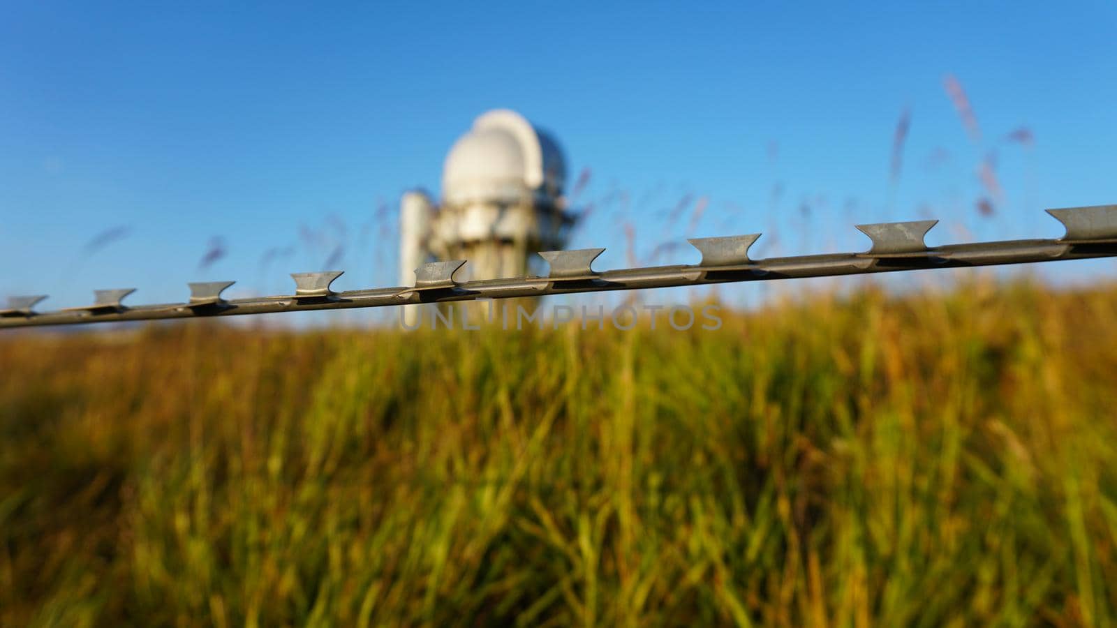 A large observatory is protected by a barbed fence by Passcal