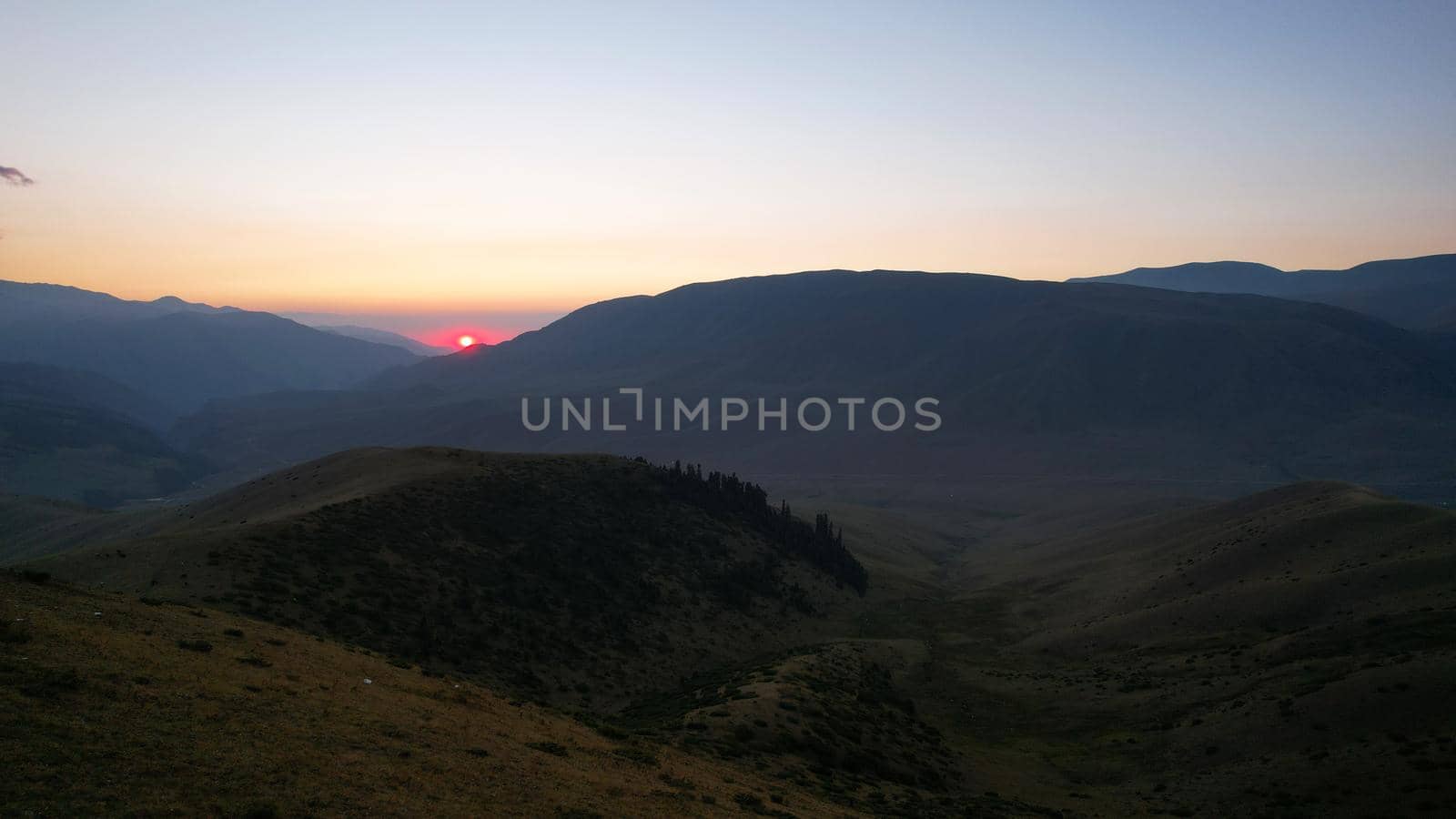 Red rays of the sun at sunset among the mountains by Passcal