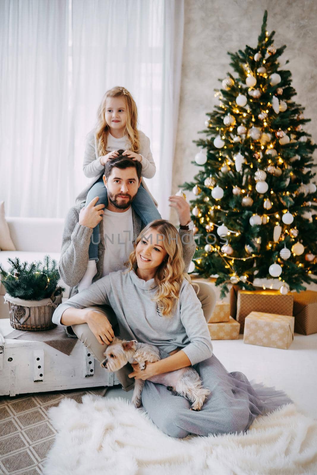 Happy family: mom, dad and pet. Family in a bright New Year's interior with a Christmas tree.