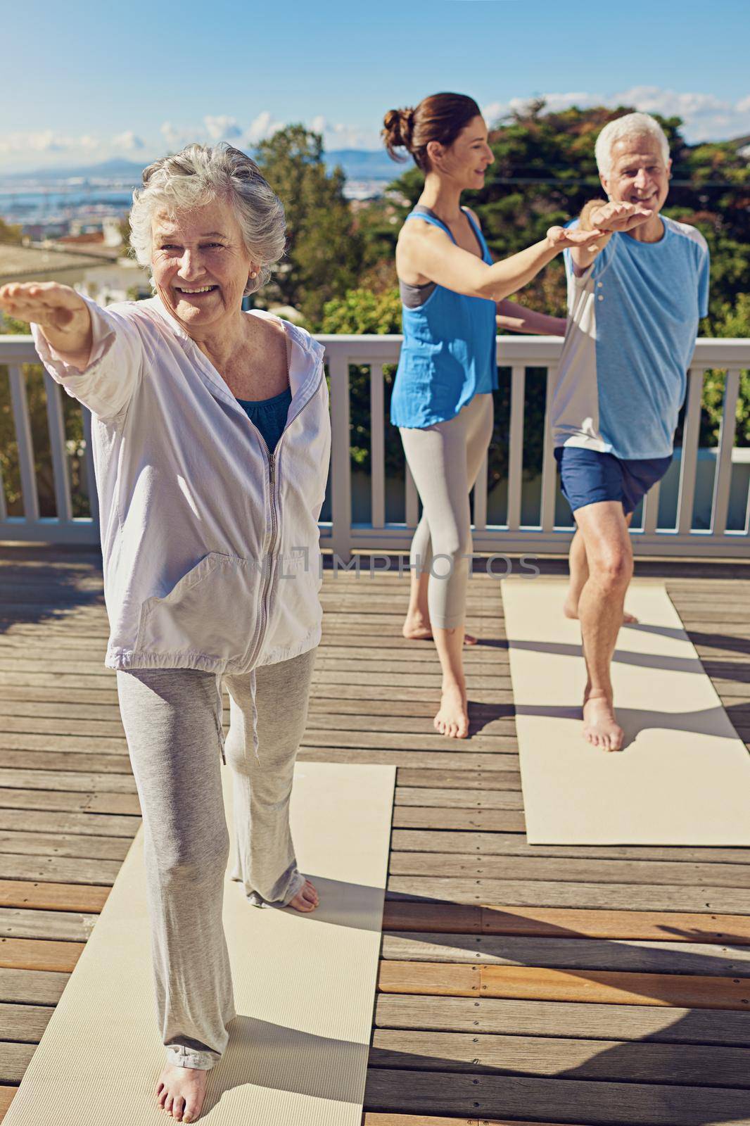 Yoga is for all ages. a senior couple doing yoga together with an instructor on their patio outside