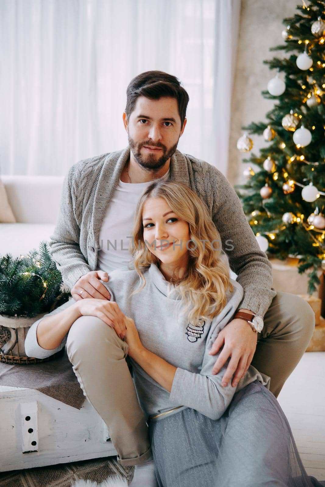 A happy couple in love - a man and a woman. A family in a bright New Year's interior with a Christmas tree by Annu1tochka