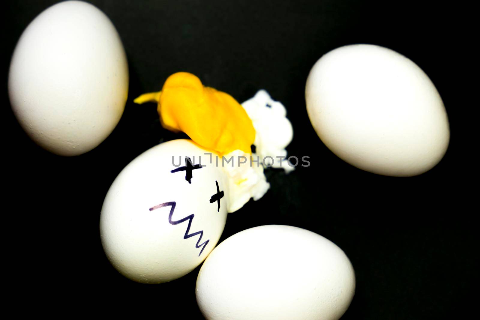 White eggs, one of them boiled and broken an simulating an accident