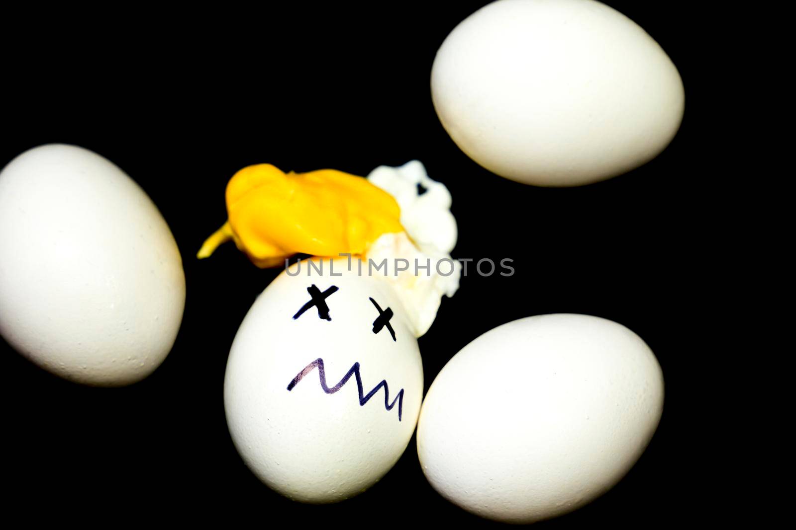 White eggs on black background and one of them boiled and simulating an accident by soniabonet
