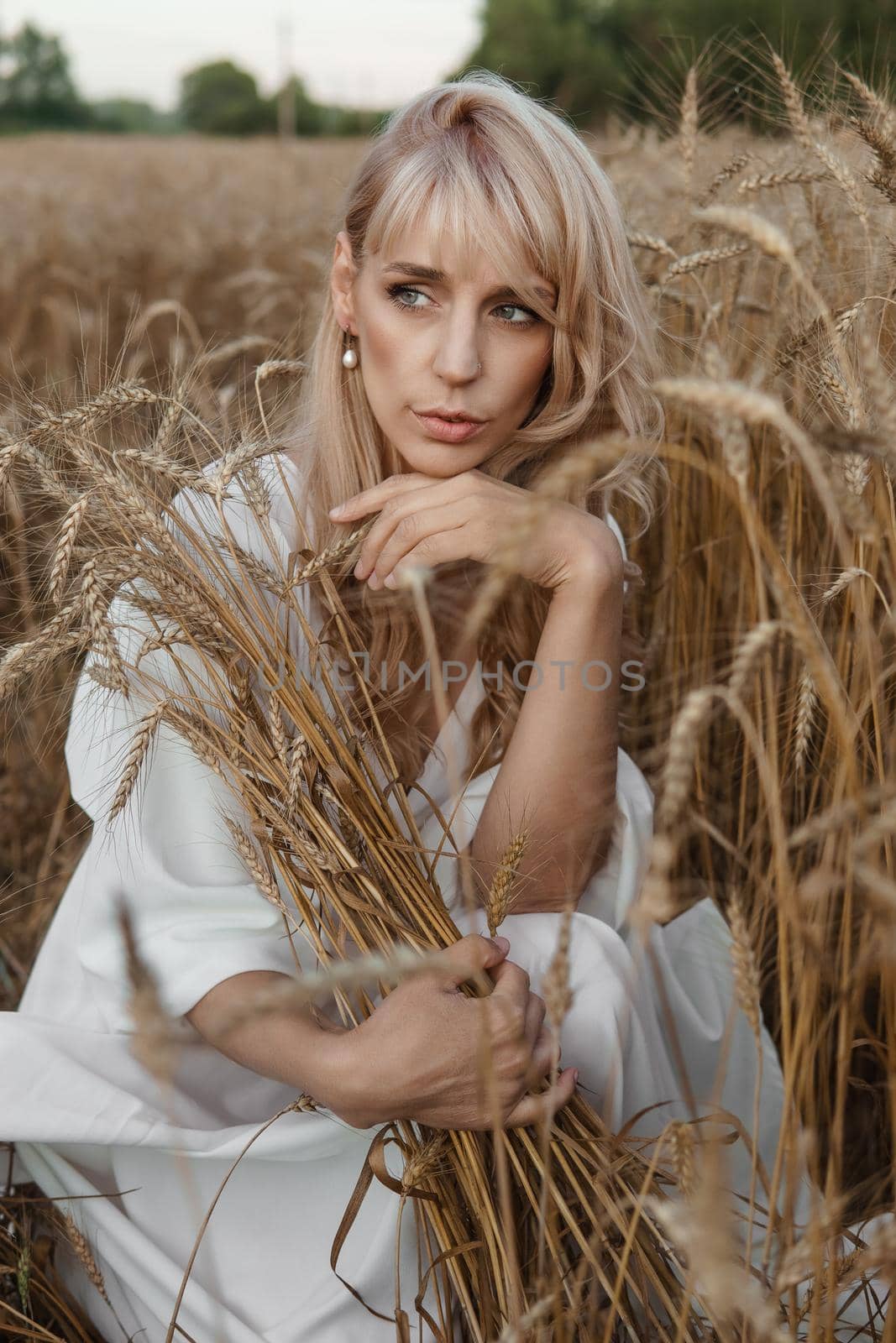 A blonde woman in a long white dress walks in a wheat field. The concept of a wedding and walking in nature by Annu1tochka