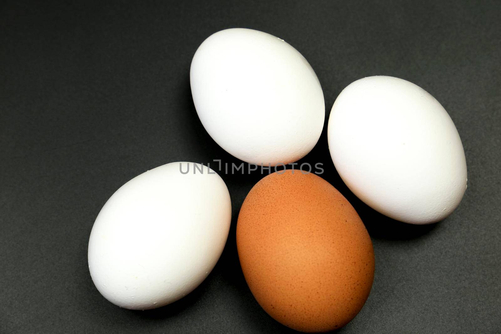 Brown and three white eggs on the table