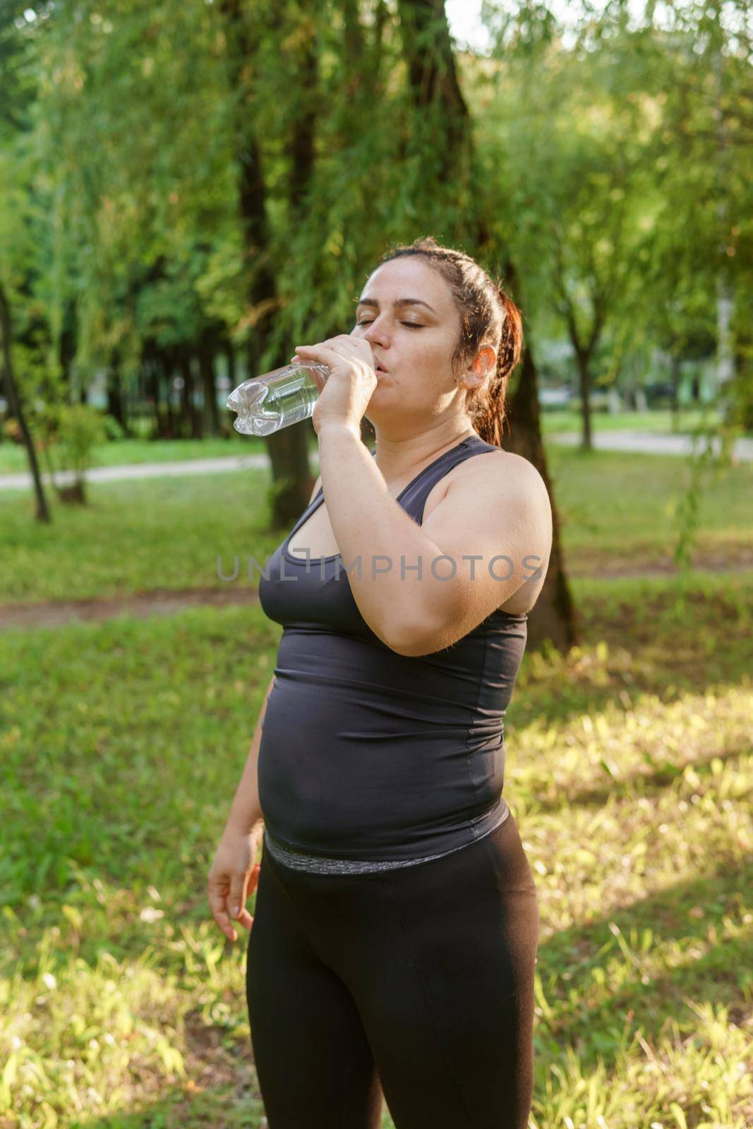 A charming brunette woman plus-size body positive practices sports in nature.