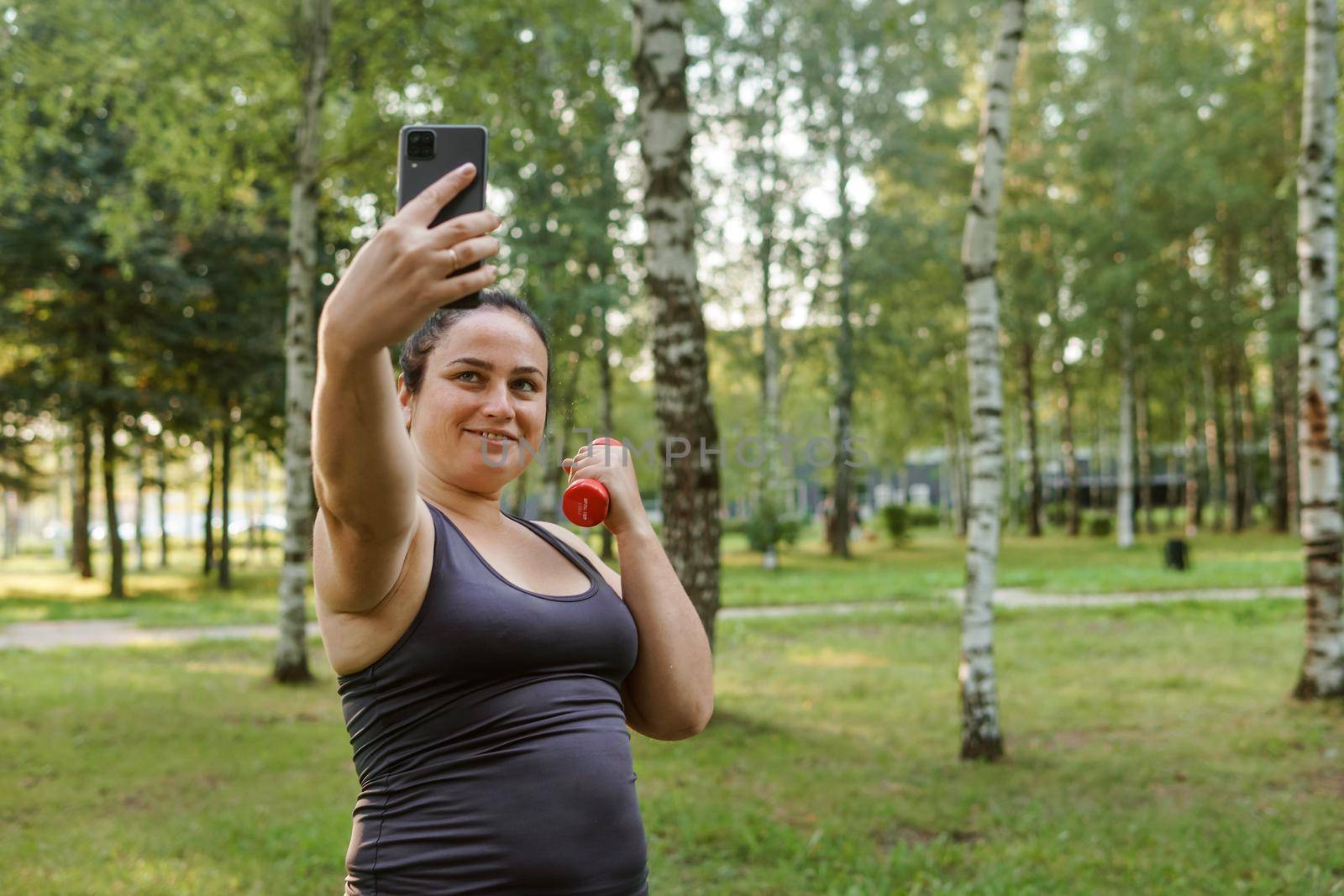 A charming brunette woman plus-size body positive practices sports in nature.