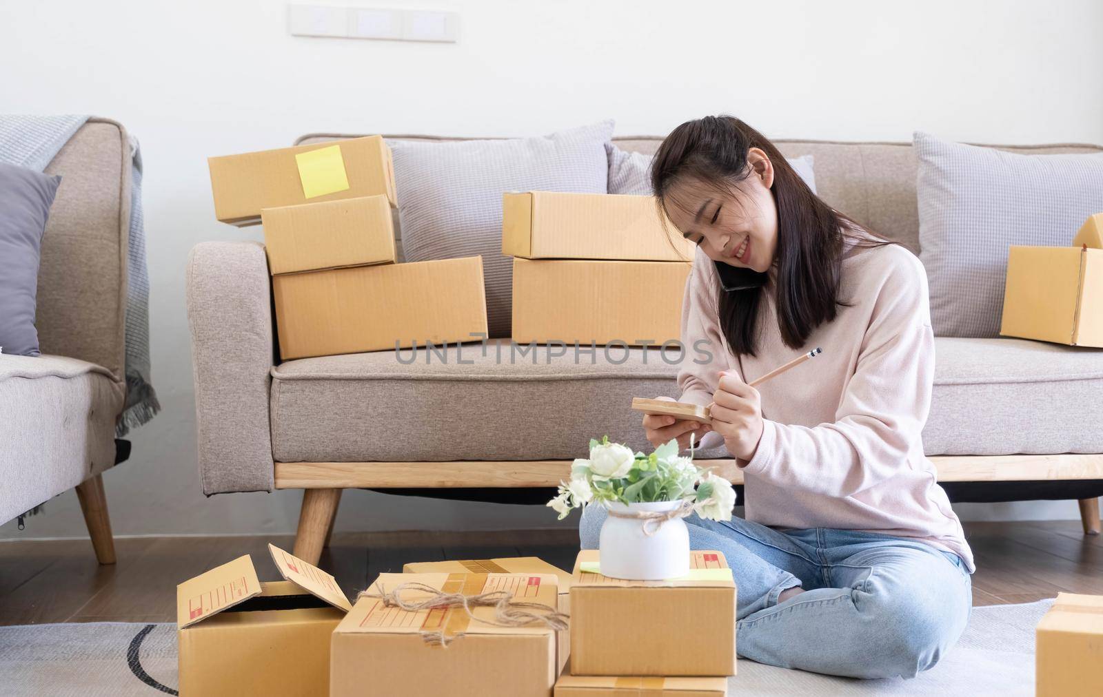 Young attractive asian woman owner startup business look at camera work happy with box at home prepare parcel delivery