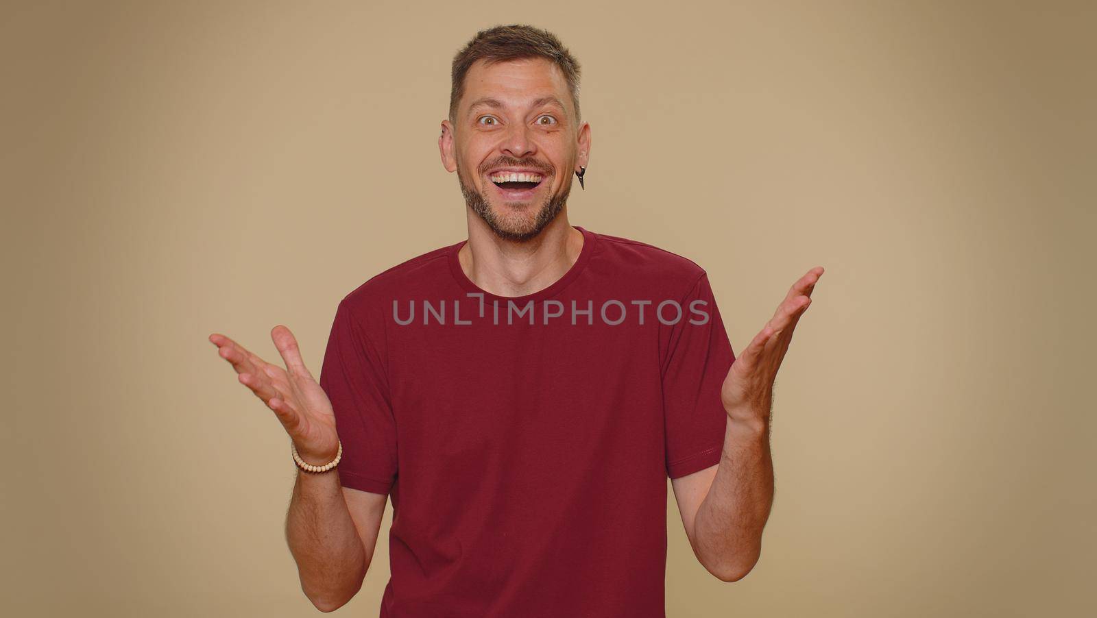 Oh my God, Wow. Excited amazed man looking surprised at camera with big eyes, shocked by sudden victory game winning, lottery goal achievemen, good news. Adult guy on beige studio background indoor