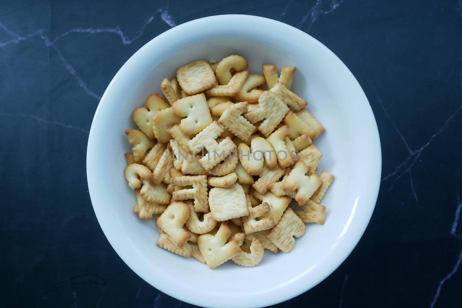 letter shape sweet cookies in a white bowl on black ,