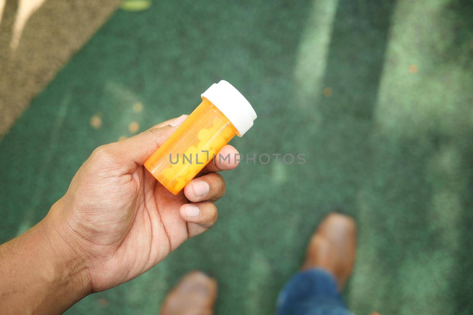 young man hand holding medicine pill container .