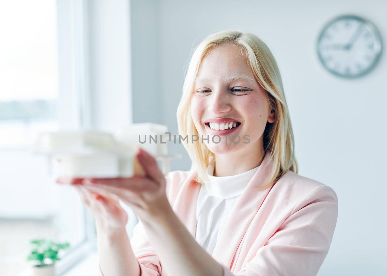 portrait of a young business woman holding a modern house model in the office