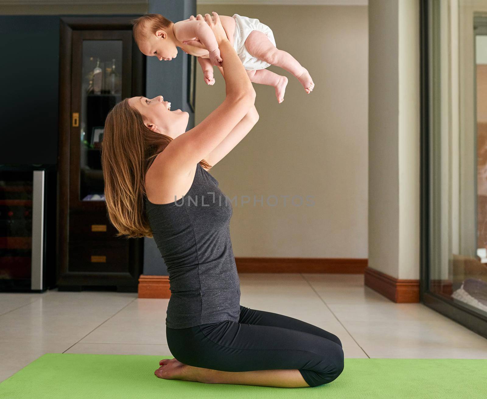 The best work out partner. a young mother and her baby at home. by YuriArcurs