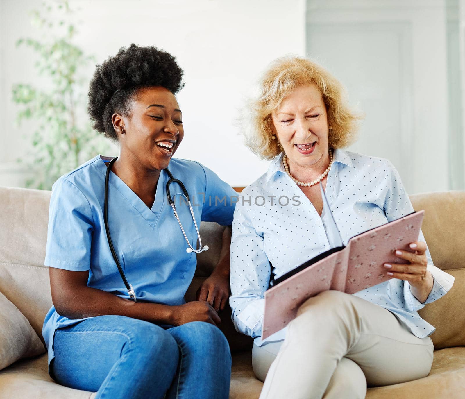 Doctor or nurse caregiver with senior woman looking at photo album and picture or book or brochure at home or nursing home