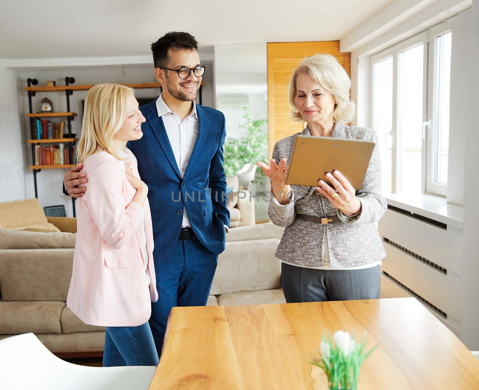 Young happy couple and an agent in a new property