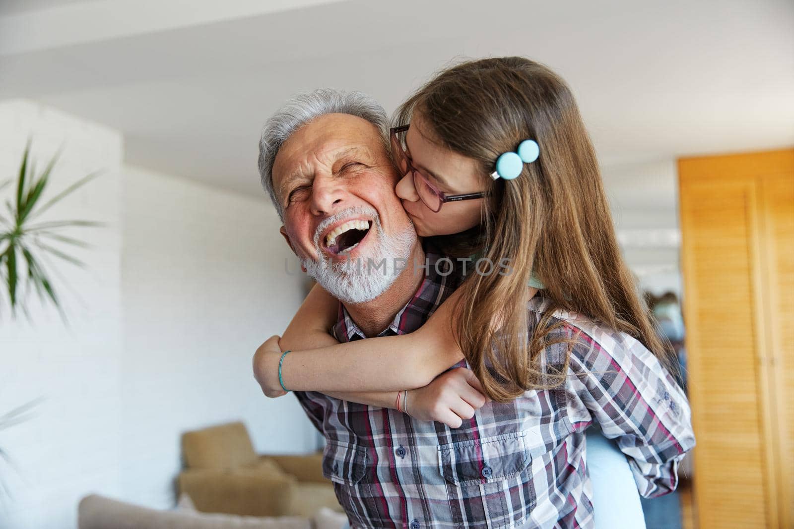 Portrait of Grandfather and granddaughter having fun hugging and bonding together at home