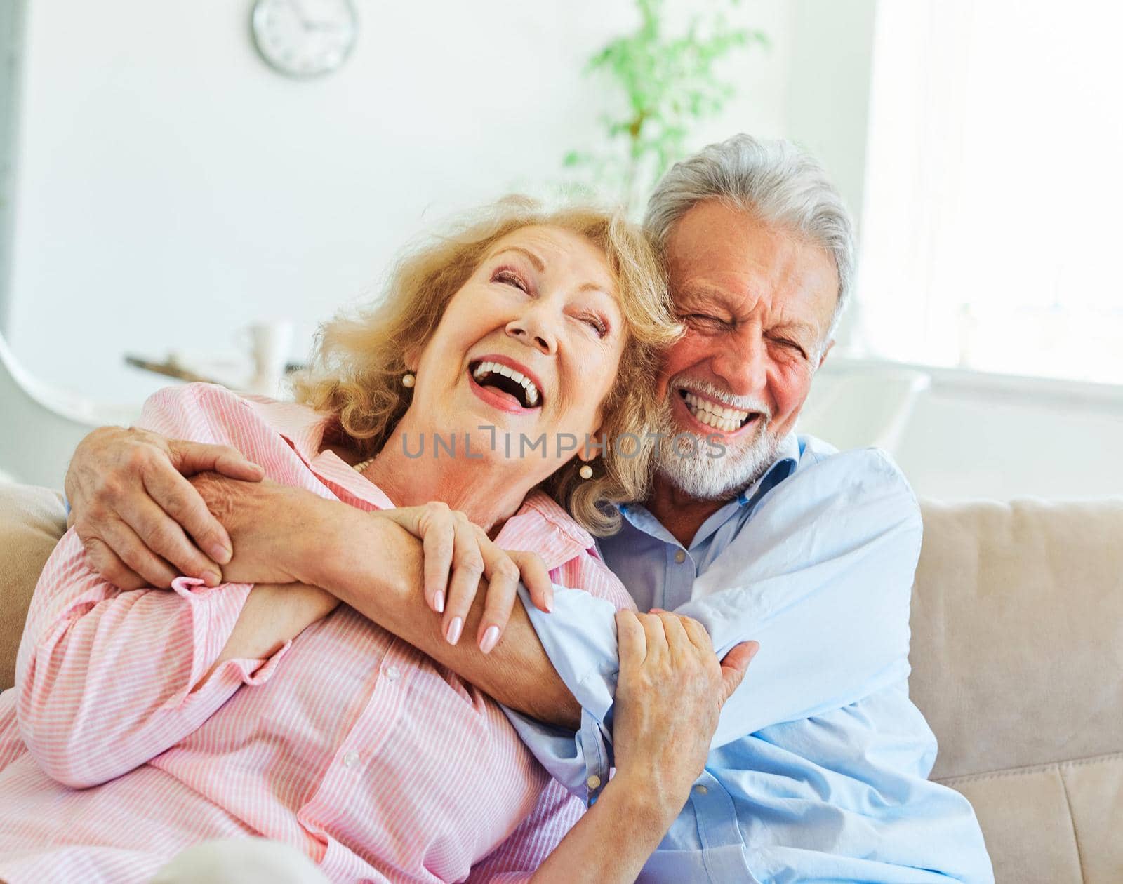 Portrait of a happy senior couple embracing hugging and having fun at home