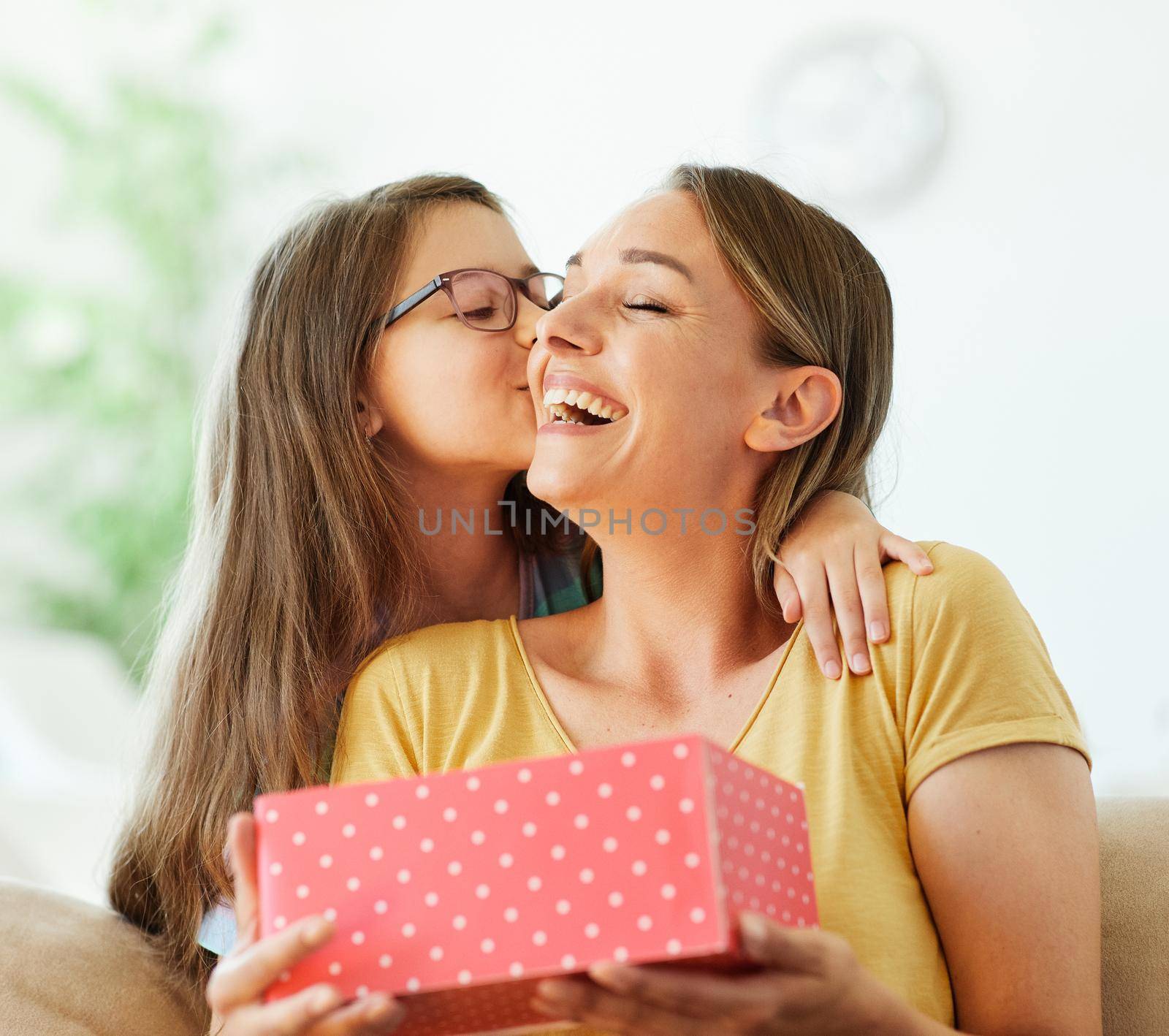 Daughter surprises her mother with present and kiss on mother's day or birthday at home