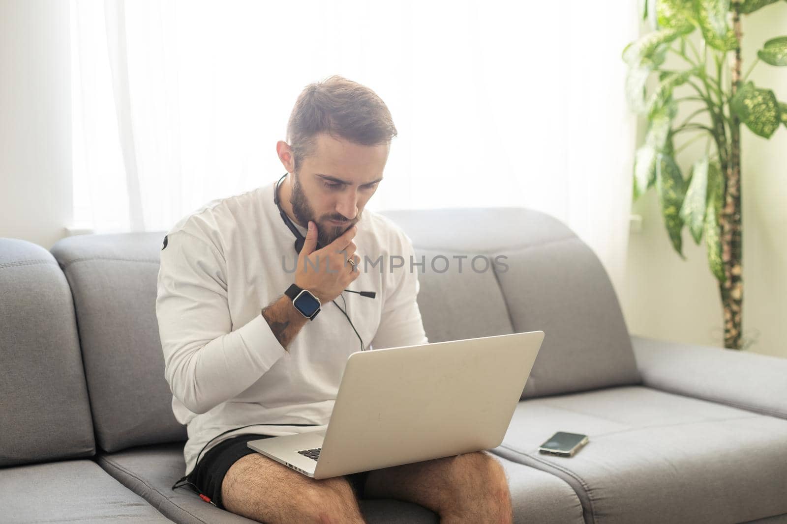 Young man freelancer using laptop studying online working from home, happy casual guy typing on notebook. by Andelov13