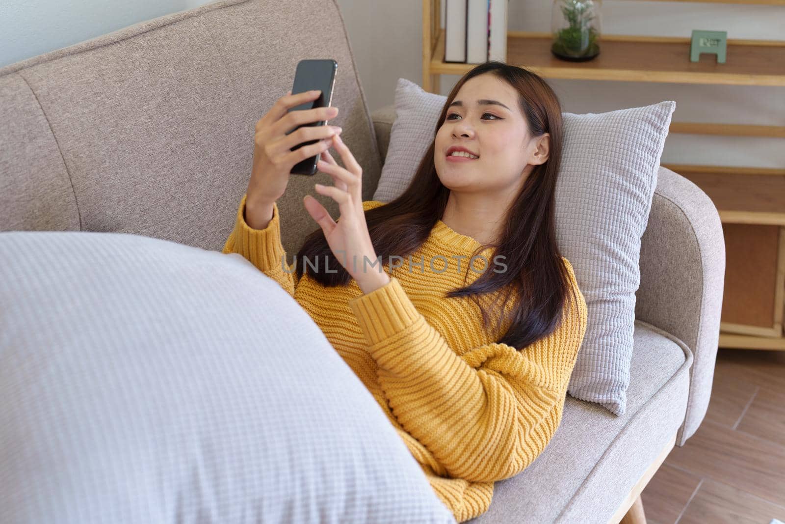woman sleeping on sofa at home ready to use mobile phone by Manastrong