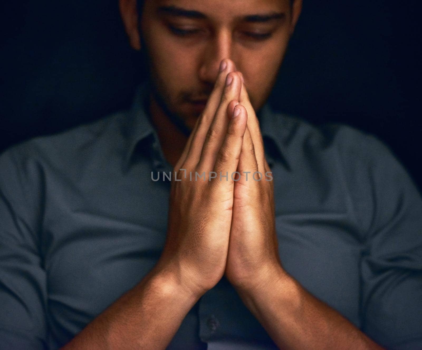 Give us this day our daily bread. Closeup shot of a young man praying with his eyes closed. by YuriArcurs